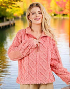 Woman wearing blush Teddy Bear Sherpa pullover with cable pattern and elbow corduroy patches by a scenic lake.