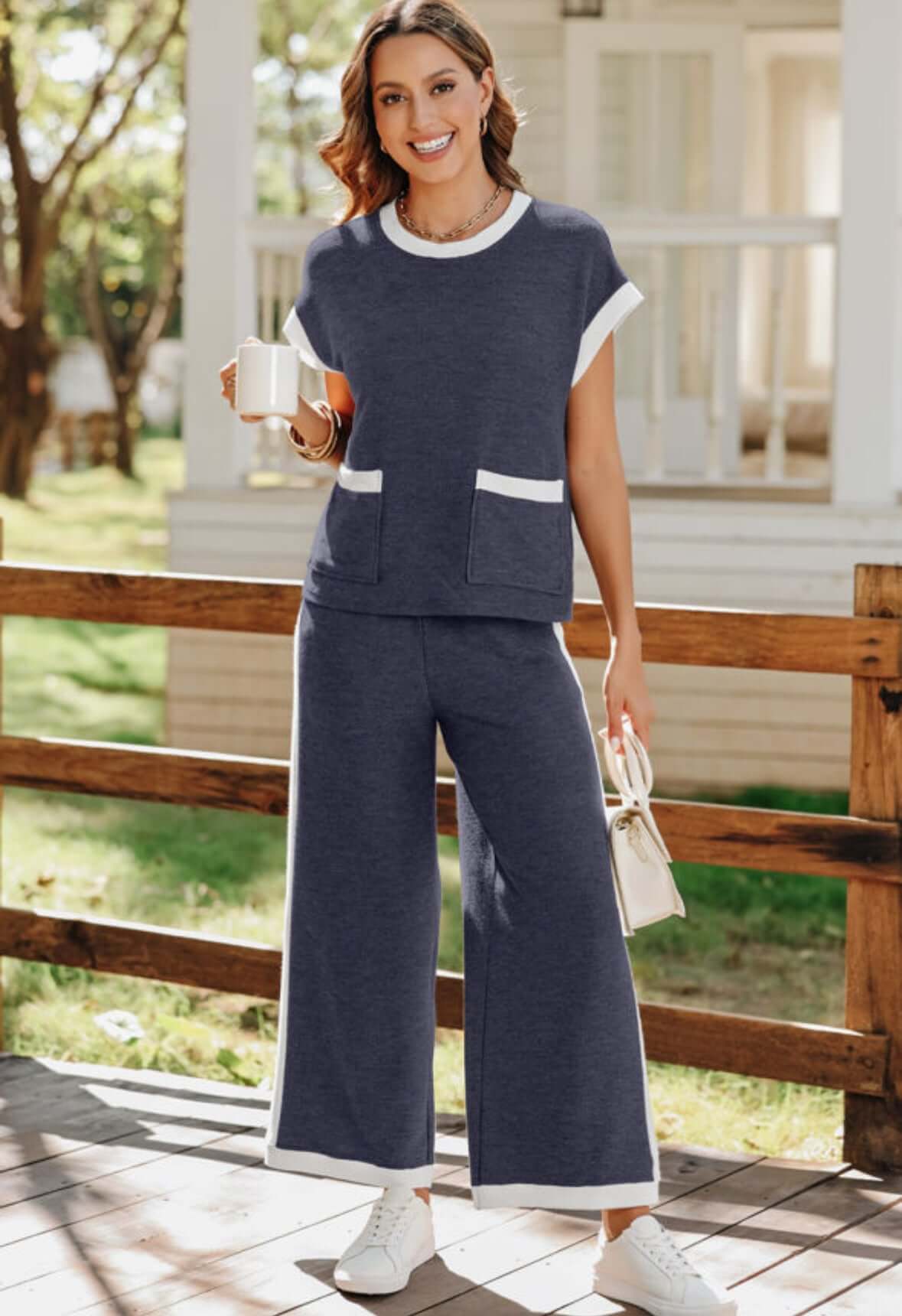 Model wearing Harbor View 2 Piece Pants Set in navy blue with white trim, holding a cup, in a sunny outdoor setting.