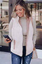 REVERSIBLE RETREAT VEST! Stylish woman wearing a pink Sherpa lined vest while checking her phone outdoors.