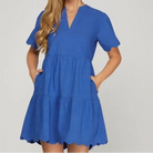 Cobalt blue tiered mini dress with scalloped sleeves and hem, featuring a V-notch neckline and pockets.
