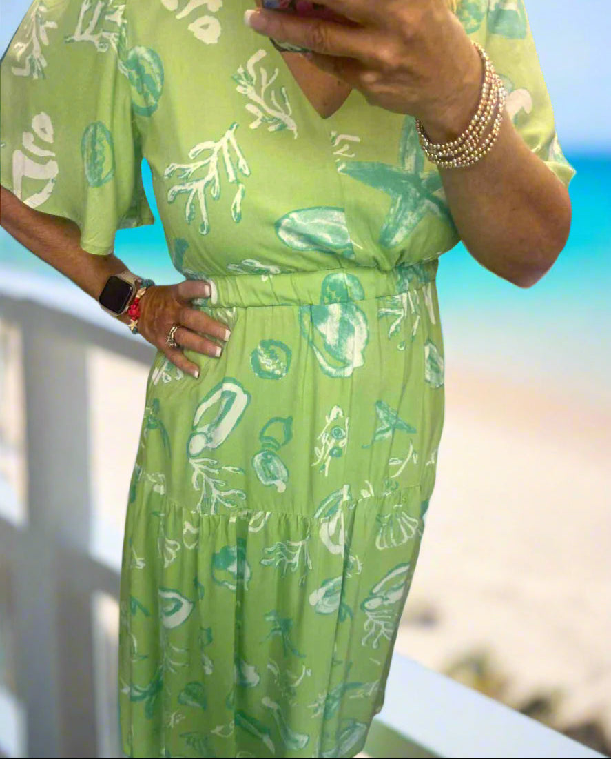 Model wearing the Seashell Serenade dress—lime green midi with seashell print, ideal for beach outings and summer fun.