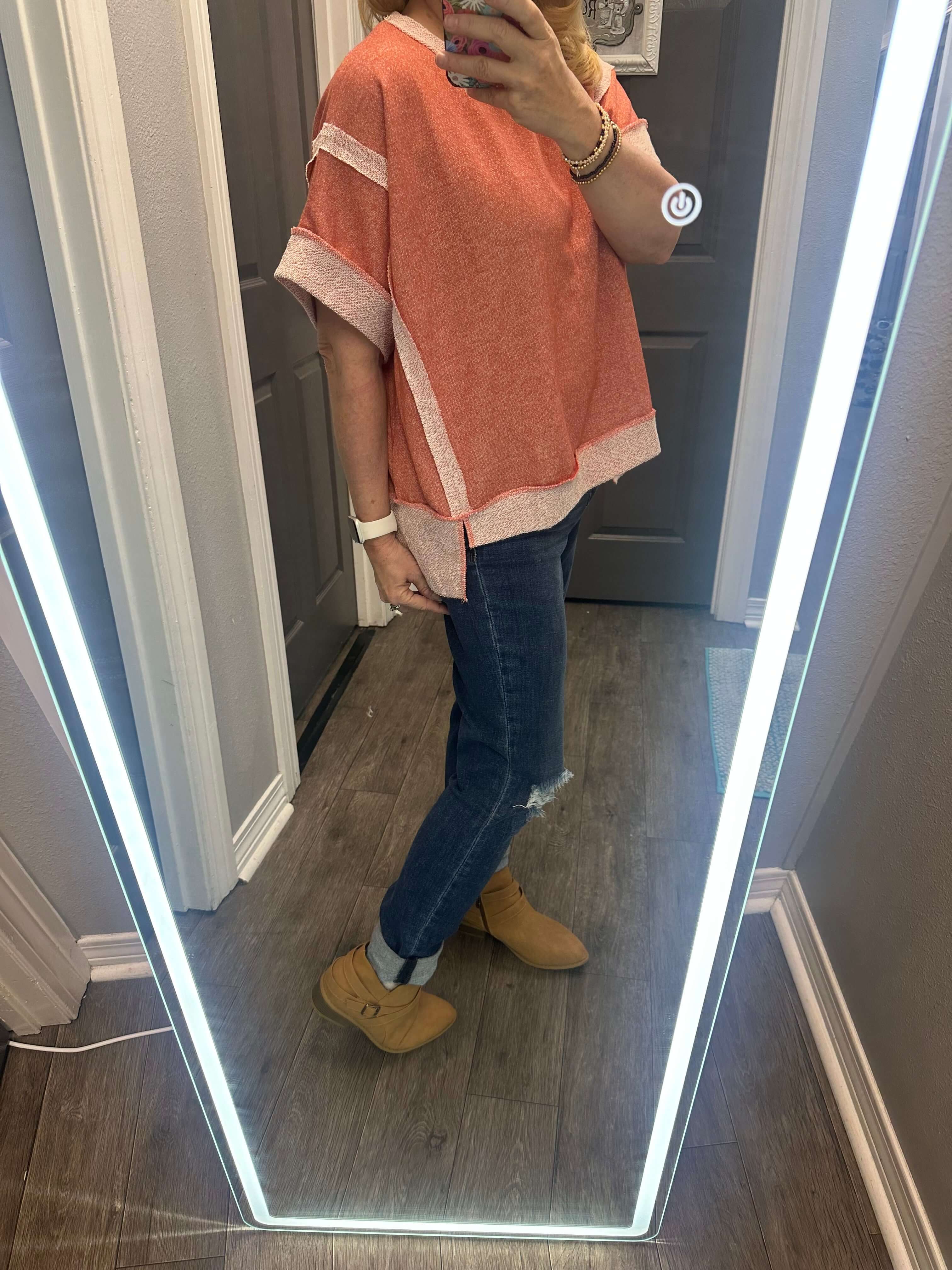 Casually Cute Top in Peach Passion worn with jeans, showcasing a stylish, relaxed fit in a mirror reflection.