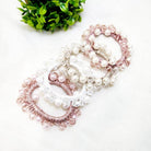 Elegant Charmed Twists hair ties in pink and white with glass beads and faux pearls, perfect for stylish ponytails.