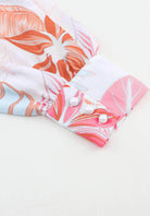 Close-up of tropical print dress sleeve with pink and orange leaves and decorative buttons.