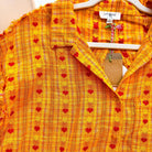 Close-up of the Hello Happiness Top by Umgee, featuring bright sunset hues and tiny red heart motifs.