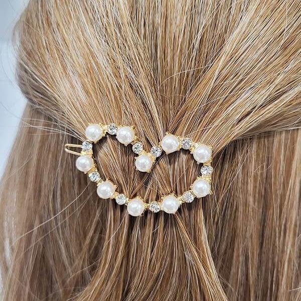 Pearl and rhinestone heart-shaped hair pin in blonde hair, showcasing elegant hairstyle accessory for special occasions.