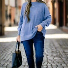 A woman wearing a light blue sweater and jeans, showcasing the CLOUDY SKY - ZENANA outfit in a stylish outdoor setting.