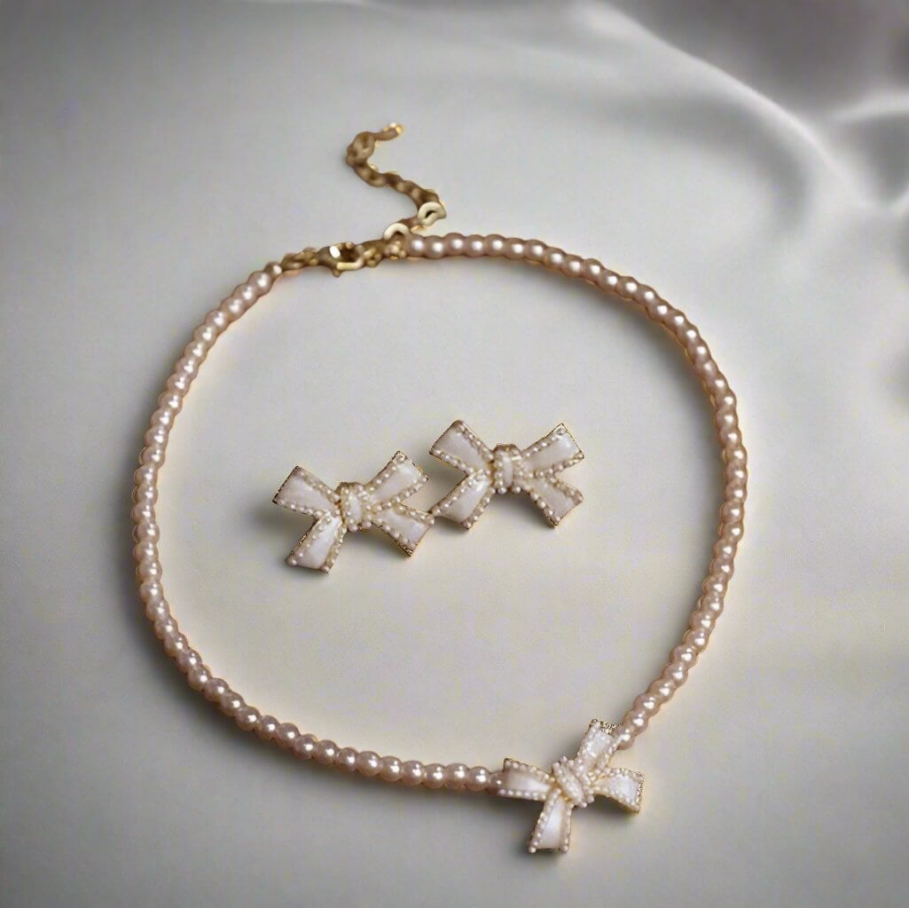 Elegant bow necklace and earrings set with faux mother of pearl and pearls, perfect for any occasion.