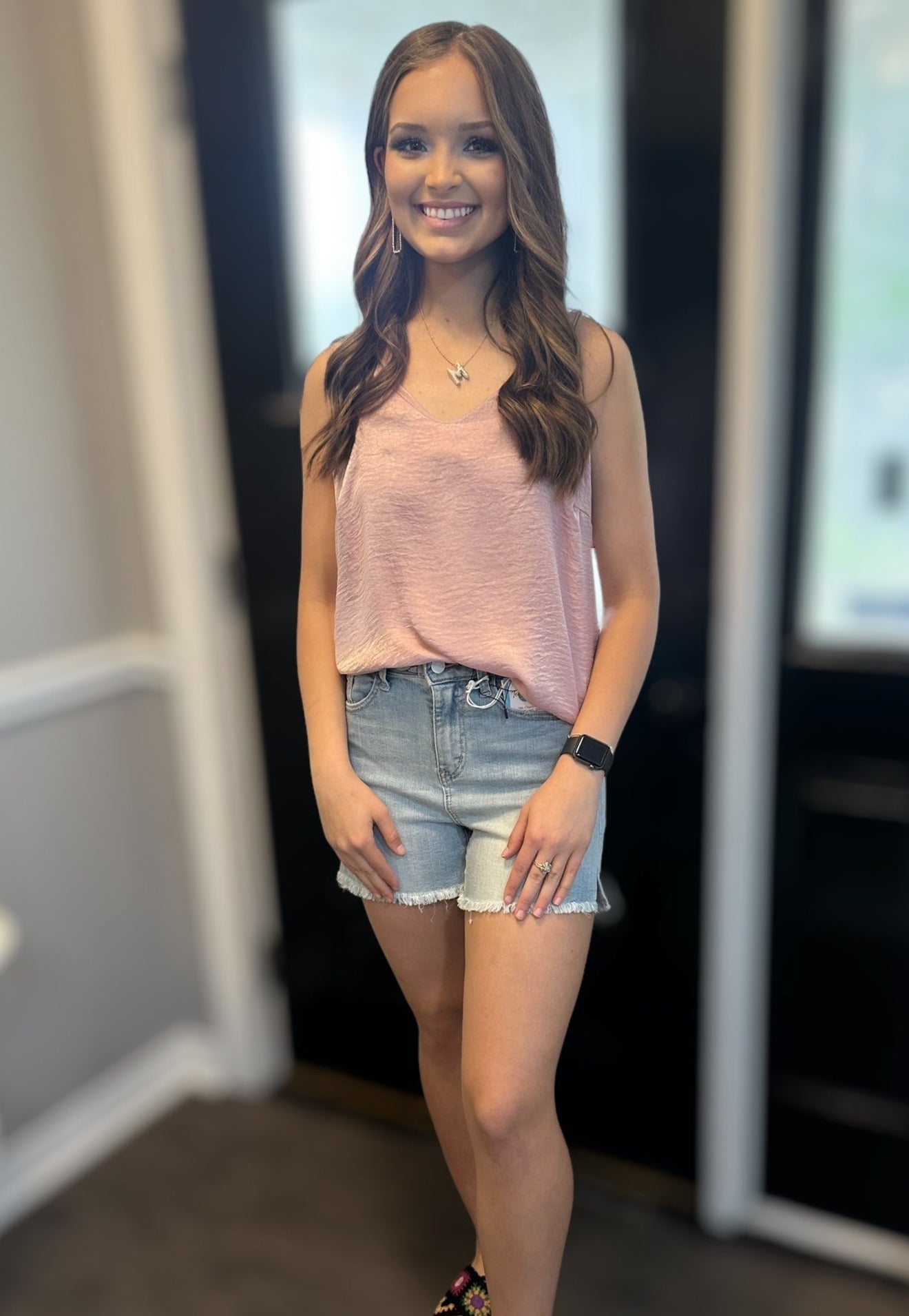 Model wearing MAGIC FIT Cami in pink with denim shorts, showcasing its stylish and versatile reversible design.