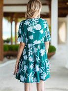 GLORIOUS DAY Dress - Jodifl by JODIFL $36.00 Enhance your style with the stunning teal green dress adorned with a beautiful baby blue floral print. This dress features a unique button-up design with pin tuck fold details, short sleeves, buttoned band cuff