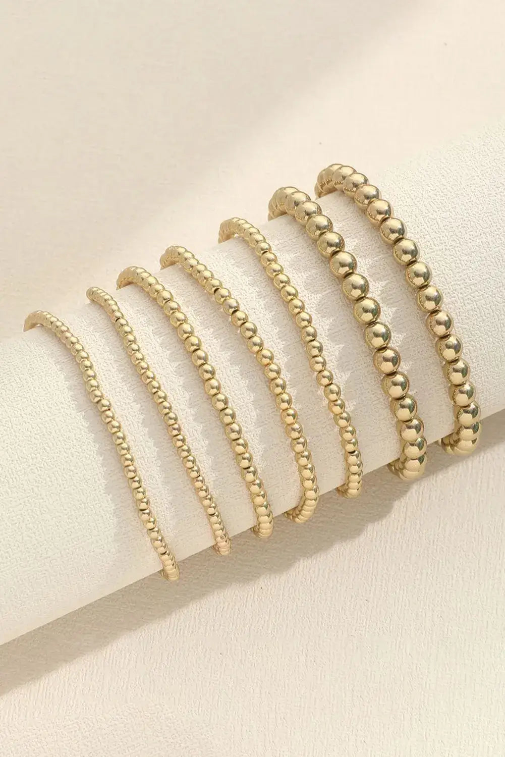 TIME TO SHINE Bracelet Set - 7 minimalist gold tone beaded bracelets on display against a light background.
