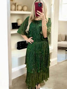 Model wearing the FEELING PRETTY green and gold midi dress by Sugarlips with tiered ruffle skirt and elegant sleeves.