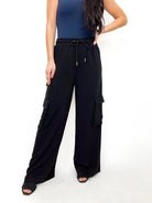 Woman wearing black cargo pants with drawstring waist and pockets by White Birch.