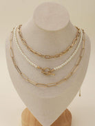 CN4261 Multi Pearl Toggle Chain Necklace Set displayed on a bust, showcasing three layered gold and pearl necklaces.