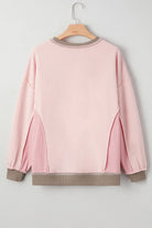 Back view of the FROM THE HEART PULLOVER featuring a soft light pink color, trendy exposed seams, and waffle-textured patchwork.