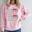 Woman wearing LOVE YOU MORE CREWNECK in pink with XOXO vinyl decal and floral details.