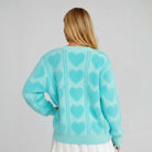 Back view of the LOVE AT FIRST SIGHT SWEATER featuring a cozy light blue color and heart pattern detailing.