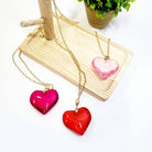 Colorful heart-shaped pendant necklaces displayed on a wooden stand, perfect for Valentine's Day gift packs.