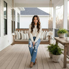 Model sitting on a porch wearing JUDY BLUE - ADDISION JEANS with a cozy sweater, showcasing a stylish casual look.