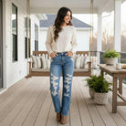 Model wearing JUDY BLUE - ADDISION JEANS with distressed details, styled for an outdoor setting.