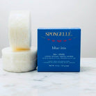 BLUE IRIS DUO BY SPONGELLE body wash infused buffers set with luxury packaging and exfoliating sponges on marble surface.