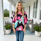 BRIGHTER DAYS TOP - Umgee model wearing vibrant floral print top on porch with stylish decor.