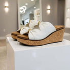 CORKYS - MISS UNDERSTOOD WEDGES in ivory with double bow and cork wedge heel on display.