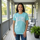 LULU MAC MINERAL AQUA & CAMO COMFORT COLOR TEE worn by a smiling woman on a porch.