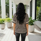 Model wearing the NATURAL EDGE TOP, a chic leopard print top, showcased in a stylish outdoor setting.