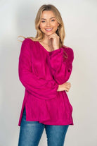 Woman wearing hot pink HAPPY WANDERER Top by White Birch with long sleeves, V-neck, side split, paired with blue jeans