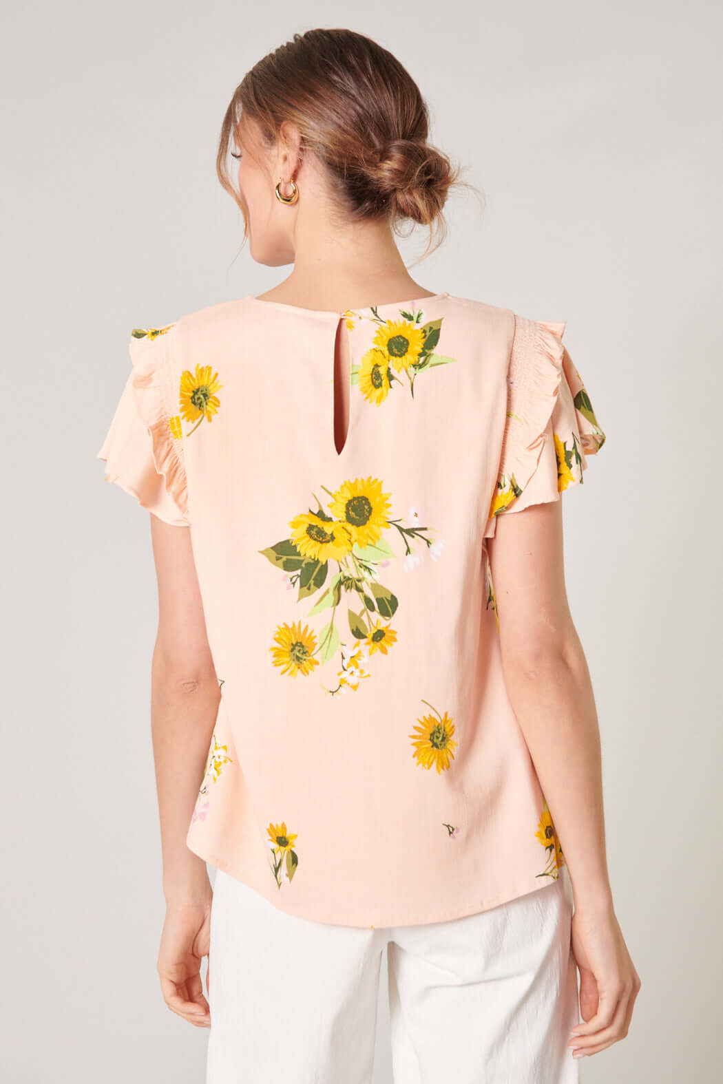 Back view of the DAISY MARIE TOP featuring sunflower prints and ruffle details in blush yellow, perfect for spring styling.