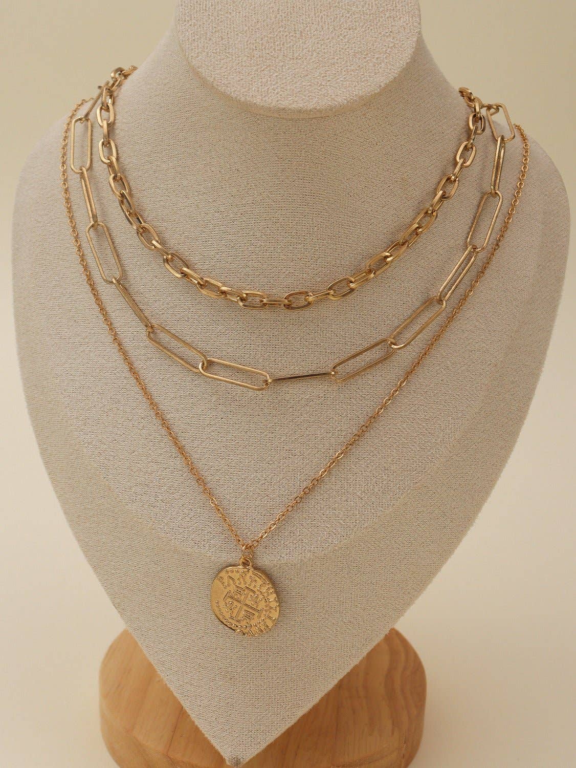 Gold multi-layer chain necklace set with pendant displayed on a jewelry stand.