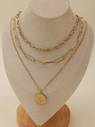 Gold multi-layer chain necklace set with pendant on display bust