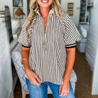 Woman wearing the CLASSIC CURRENT TOP with black stripes and half zip neckline, showcasing sporty and chic style.