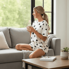 MOMENT IN TIME - 2 PIECE SHORTS SET featuring a model relaxing with a cup of coffee in a stylish polka dot outfit.