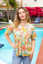 Young woman wearing an oversized floral peplum knit top by Haptics, standing by a pool.