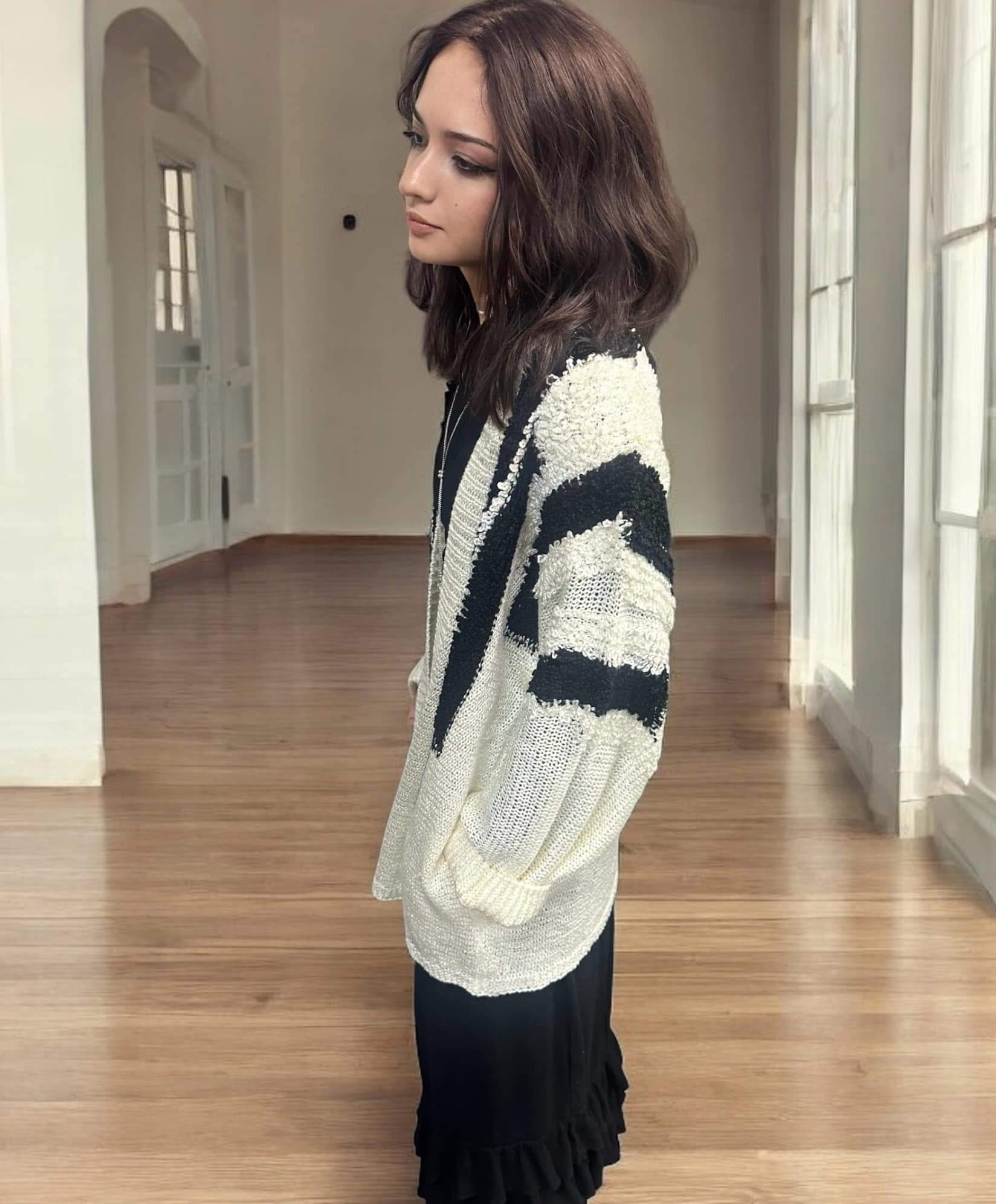 Woman wearing an ivory and black Ultra Soft Cardigan by KyeMi, showcasing its fuzzy texture and stylish design with pockets.