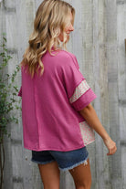 Model wearing a fuchsia floral color block pullover with wavy rib details over denim shorts.