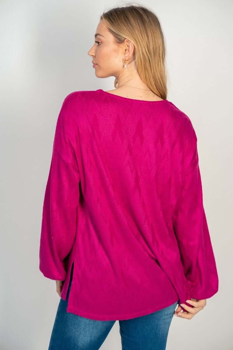 Woman wearing the Happy Wanderer hot pink long sleeve top by White Birch, showcasing the woven pattern and side split design.