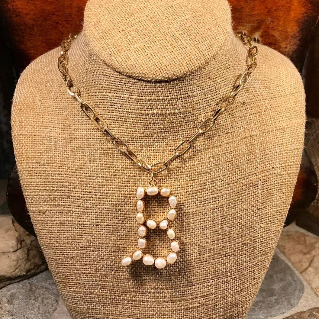 Elegant pearl essence monogram necklace on display with gold-tone chain, Avenue Zoe brand, featuring delicate freshwater pearls.