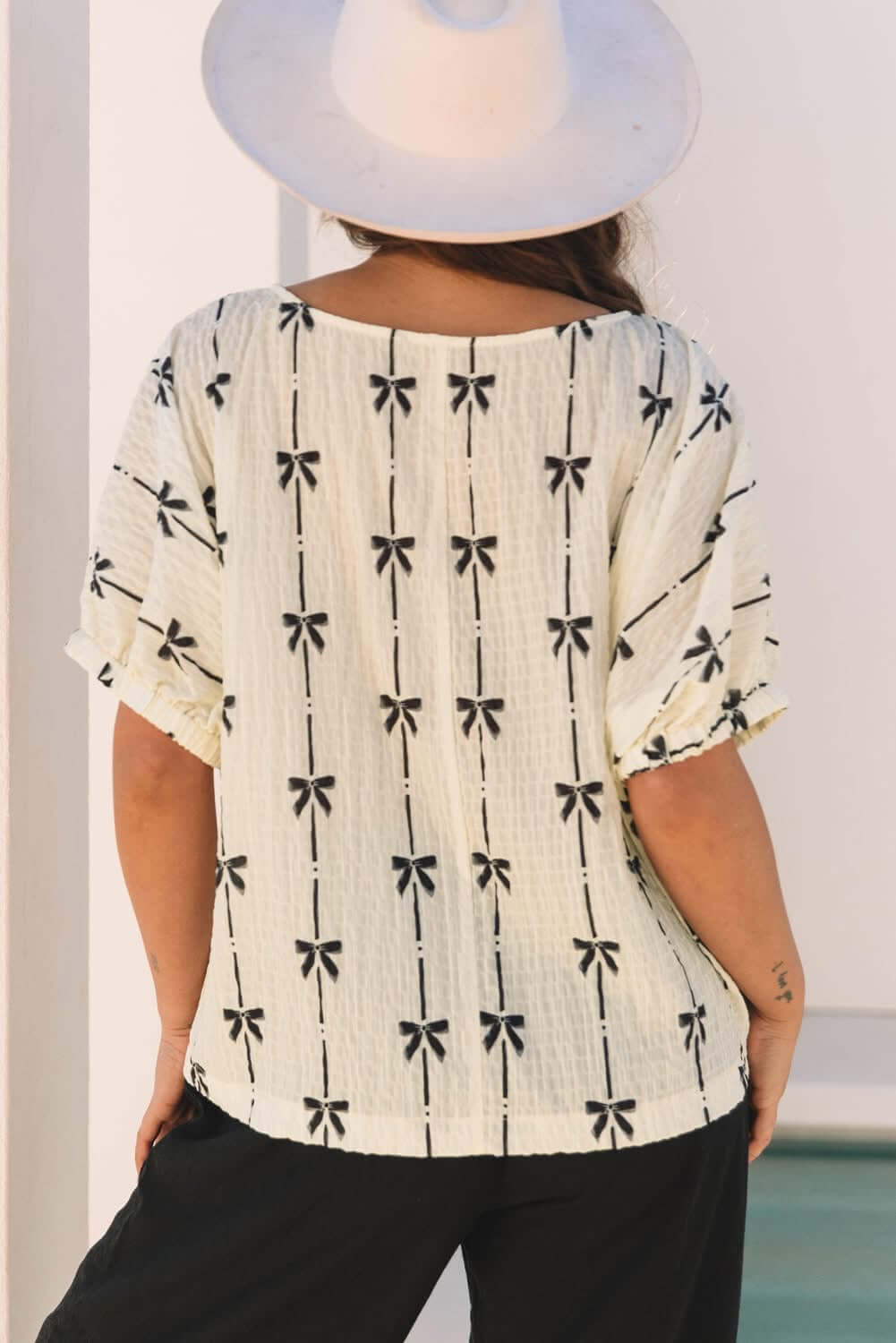 Back view of the Ribbons in the Sand top featuring a playful bow pattern and a casual, relaxed fit.