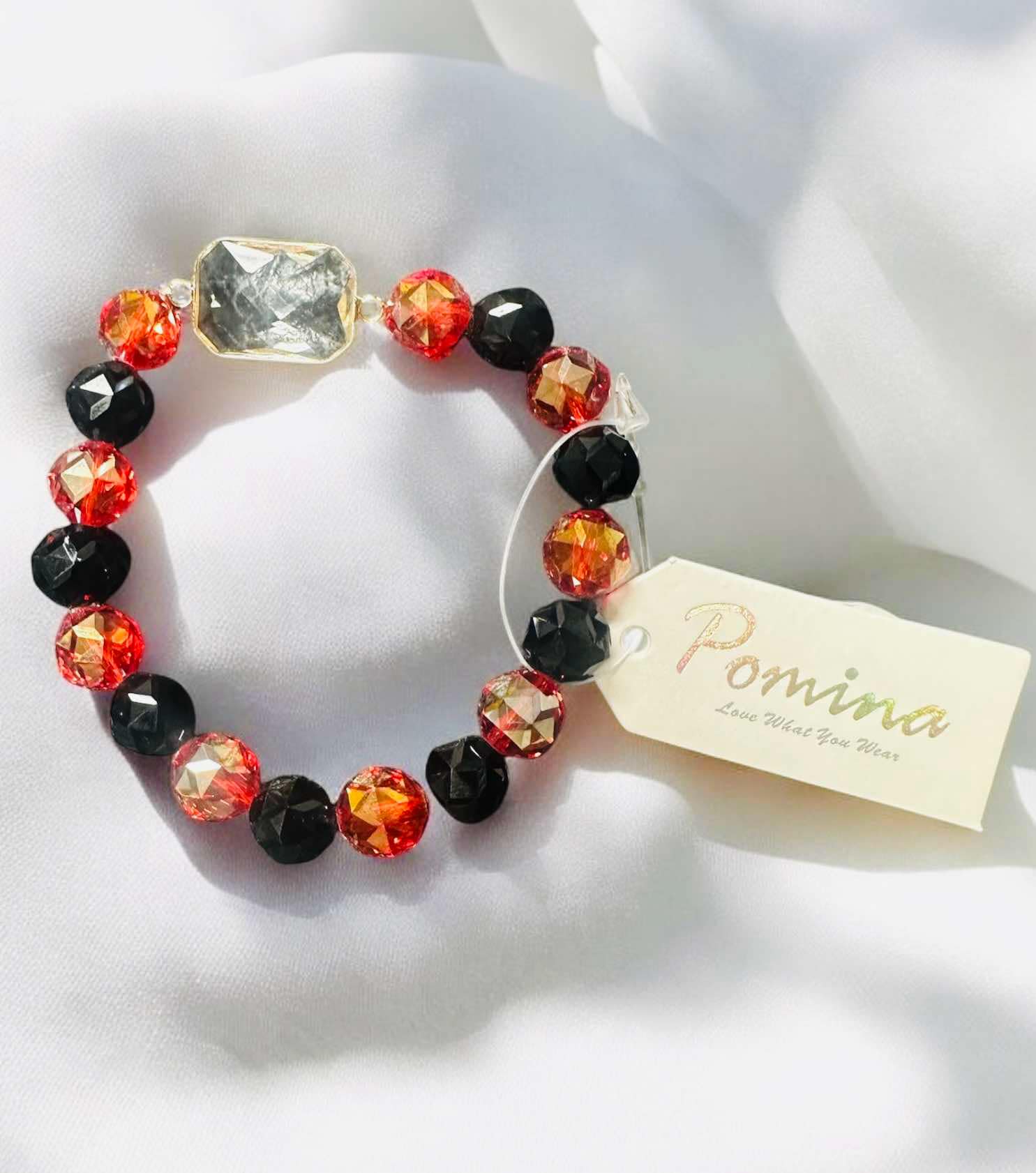 Stackable Pomina bracelet featuring black and fiery red beads with a large rectangular glass gemstone.