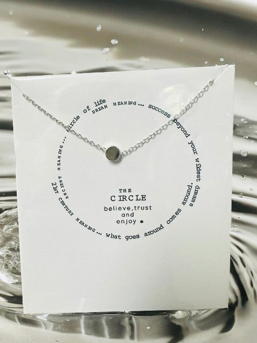 Silver toned necklace featuring a circular pendant and uplifting quote on presentation card.