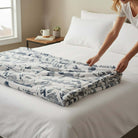 Cozy SNOWY MOUNTAIN PLUSH THROW BLANKET being arranged on a bed, perfect for adding style and warmth to any room.