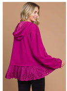 Woman wearing berry-colored ADVENTURE AWAITS Cotton Bleu hoodie with eyelet ruffle, back view.