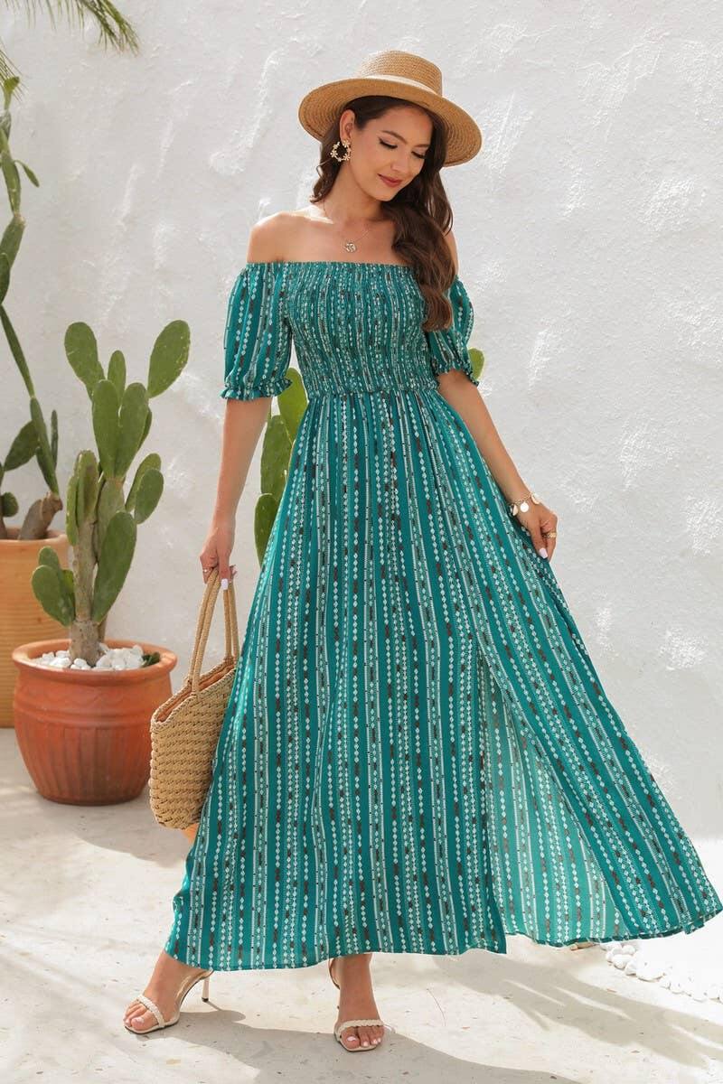 Model wearing a teal off-the-shoulder maxi dress with a slit, accessorized with a hat and a woven bag.