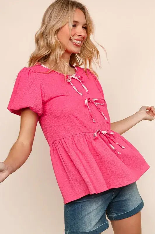 Stylish pink babydoll blouse with ribbon bows and peplum hem, perfect for summer outfits.