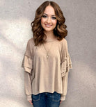 Neutral tan Soft Landing Top with double ruffles and long sleeves, worn by a woman with wavy hair, featuring a relaxed fit.