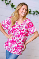 Model wearing a magenta and white geometric floral V neck top with banded sleeves, styled casually for a relaxed look.