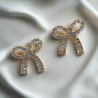 Elegant gold tone DAINTY BOW earrings by Vivian-Lu, embellished with sparkling white rhinestones, 1/2" x 1/4".